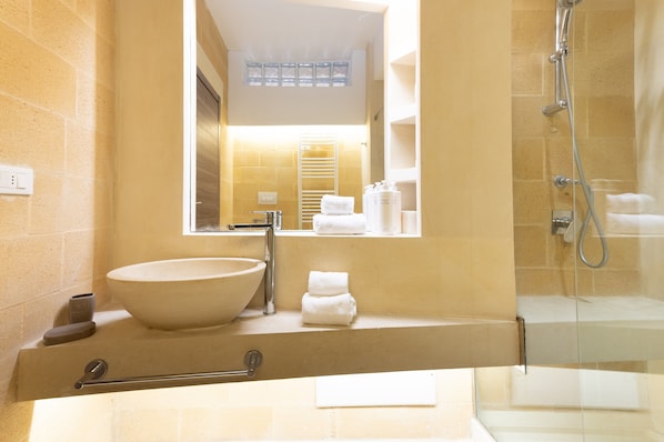 A bathroom with a large sink, a mirror, a shower, and a towel rack.