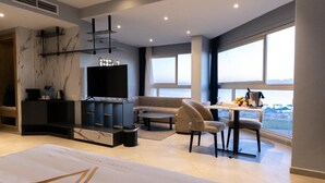 Ein modernes Wohnzimmer mit einer Couch, einem Fernseher, einer Essecke und Meerblick.