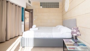 Una habitación de hotel moderna con una cama, una mesita de noche, una lámpara y vistas al baño.