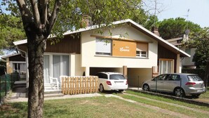 A two-story building with a garage, a fenced yard, and two cars parked in front.