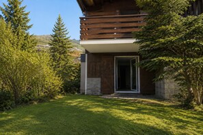 Un bâtiment moderne doté d’une façade en bois, d’une base en pierre et d’une entrée avec une porte en verre.