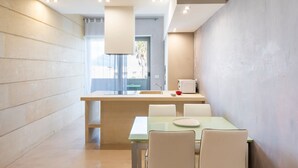 Een moderne keuken met een centraal eiland, een eethoek met een tafel en stoelen, en uitzicht op de omgeving door een raam.