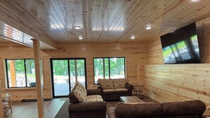 Un intérieur en bois avec un canapé, un téléviseur et de grandes fenêtres.
