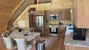 L’intérieur d’une cabane en bois comprend un coin repas, une cuisine et un escalier menant à une mezzanine.