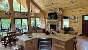 Une cuisine spacieuse avec une cheminée en pierre, des meubles en bois et un grand îlot central.