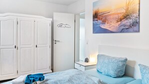 Um quarto com cama, mesa de cabeceira, um quadro na parede e um guarda-roupa.