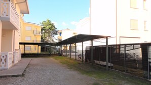 A courtyard with a gravel path, covered seating areas, and a fenced area with bicycles. - Apartment Close to the Thermal Baths (San Michele al Tagliamento)