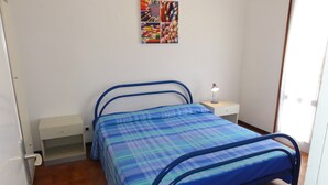 A bedroom with a bed, a bedside table, a nightstand, and a wall-mounted picture. - Apartment Close to the Thermal Baths (San Michele al Tagliamento)