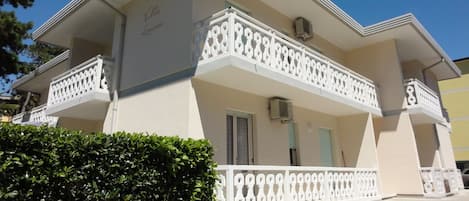 A two-story building with a balcony, a door, and a window.