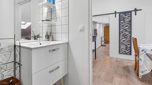 Een moderne badkamer met een wit wastafelmeubel, een spiegel en een douchehoek.