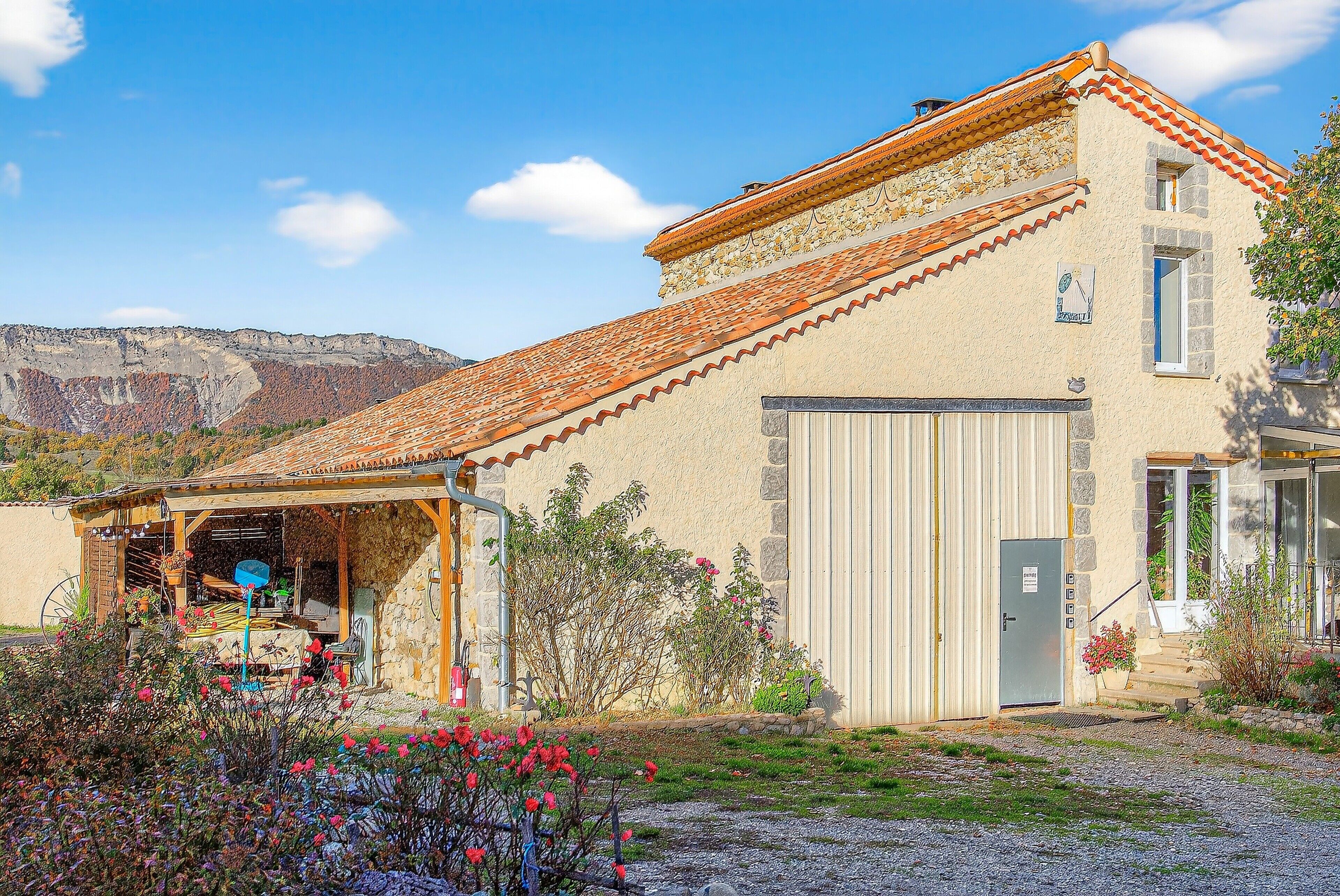 Un edificio rústico con techo de tejas, garaje y un patio cubierto.