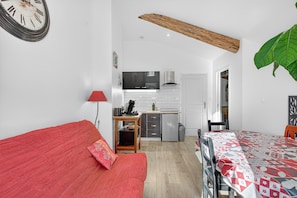 A compact living space with a kitchenette, a dining area, and a red sofa.