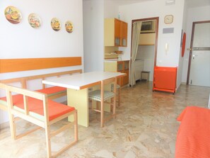 Una cocina compacta con comedor, que incluye un banco, una mesa y sillas.