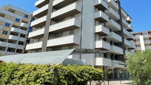 A multi-story residential building with balconies, a flat roof, and a clear sky.