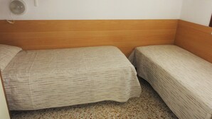 A small room with two single beds, a wooden headboard, a small shelf, and a wall-mounted light fixture. - Quiet Villa Near the Beach (San Michele al Tagliamento)