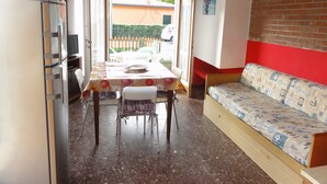 A compact living space with a dining area, a sofa, and a kitchen area. - Quiet Villa Near the Beach (San Michele al Tagliamento)