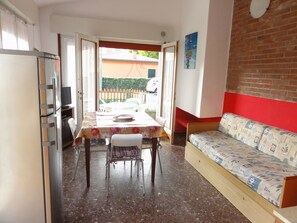 Un espacio habitable compacto con zona de comedor, sofá y cocina.