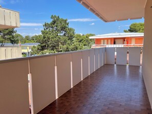 Un balcon doté d’un sol carrelé et offrant une vue sur un bâtiment équipé de panneaux solaires.