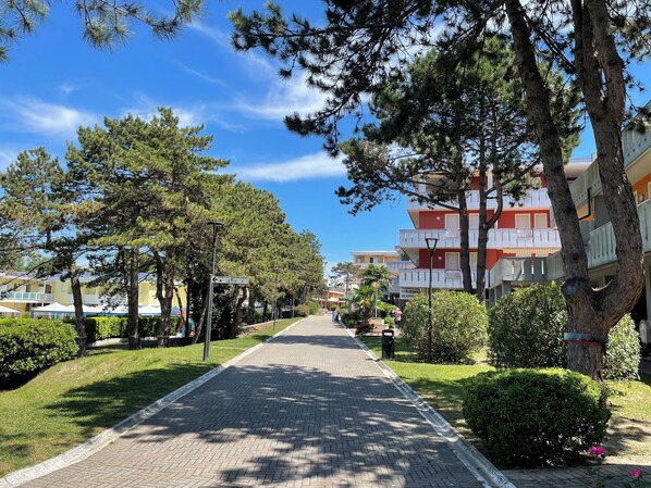 Un sendero pavimentado bordeado de árboles y un edificio con balcones.