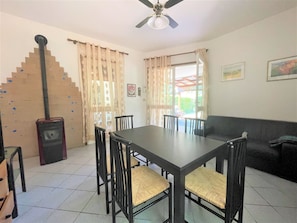 A dining area with a table and chairs, a ceiling fan, and a staircase with a decorative railing. - Bibione Pineda Villa With Private Garden (San Michele al Tagliamento)