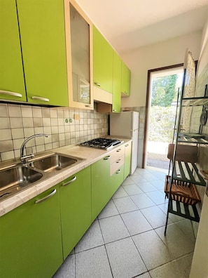 A kitchen with green cabinets, a white stove, and a sink. - Bibione Pineda Villa With Private Garden (San Michele al Tagliamento)
