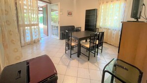 A dining area with a table and chairs, a ceiling fan, and a television on a stand. - Bibione Pineda Villa With Private Garden (San Michele al Tagliamento)