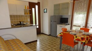 A compact kitchen with a dining area, a sofa, and a television.