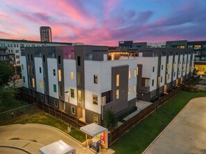 Un edificio residencial moderno de varios pisos con techo plano, ventanas amplias y un césped bien cuidado.