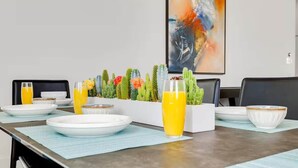 A dining table set with plates, glasses, and a cactus plant. - Designer Dallas Home, Rooftop, Kid Friendly Stay (Dallas)