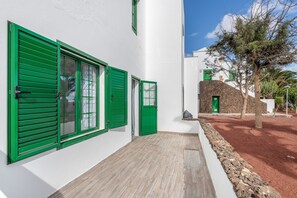 A building with green shutters, a stone wall, and a tree.