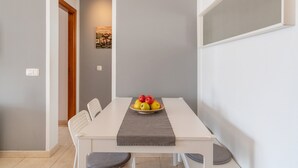 Un comedor con una mesa dispuesta para dos personas, un frutero en la mesa y vista al pasillo.