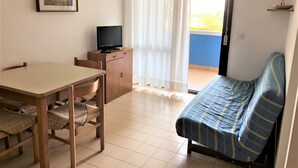 A room with a bed, a desk with a chair, a television on a cabinet, and a painting on the wall. - Bright Flat With a Large Balcony (San Michele al Tagliamento)