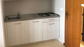 A kitchen with light wood cabinets, a stainless steel sink, and a gas stove. - Bright Flat With a Large Balcony (San Michele al Tagliamento)
