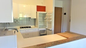 Eine moderne Küche mit weißen Schränken, einer Granit Arbeitsplatte und einem eingebauten Backofen.