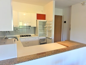 Eine moderne Küche mit weißen Schränken, einer Granit Arbeitsplatte und einem eingebauten Backofen.