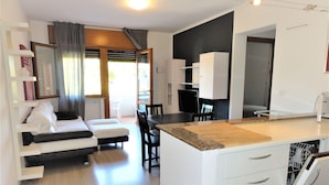 Eine moderne Küche mit weißen Schränken, einer Holz Arbeitsplatte und einem Essbereich mit einem weißen Sofa und Stühlen.