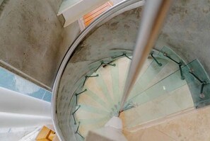 Een wenteltrap met glazen balustrades en metalen leuningen.