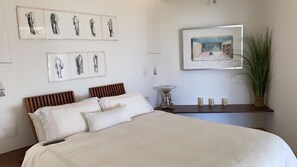 A bedroom with a large bed, two bedside tables, and wall art.