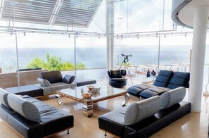 A modern living room with a large glass window, a sofa set, and a coffee table.