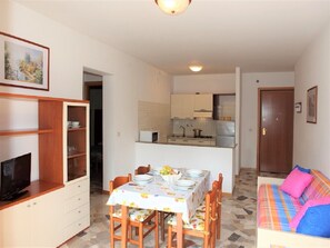 A compact living space with a dining area, kitchenette, and a bedroom with a colorful bed.