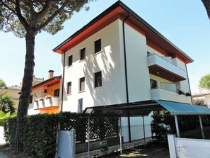 Um edifício de vários andares com telhado plano, varanda no andar superior e área externa coberta.