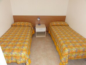 A small, simple room with two single beds, a nightstand, and a lamp. - Great Flat Close to the Beach (San Michele al Tagliamento)