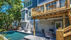 A backyard with a swimming pool, outdoor seating, and a wooden deck. - Modern Vacation Home w/ Private Pool (Hilton Head Island)