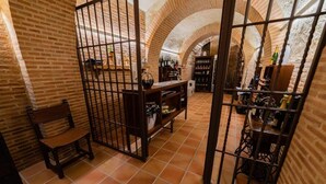 Una bodega con paredes de ladrillo, una silla de madera y estantes llenos de botellas de vino.