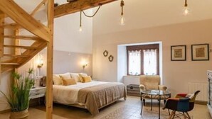Un dormitorio acogedor con techo de madera, una cama, una mesita y una silla.