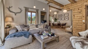 A cozy living room with a sofa, coffee table, and fireplace. There is a dining area with a table and chairs. - Charming Chalet | 168m2 | 6 pax | Familial | View (Les Houches)
