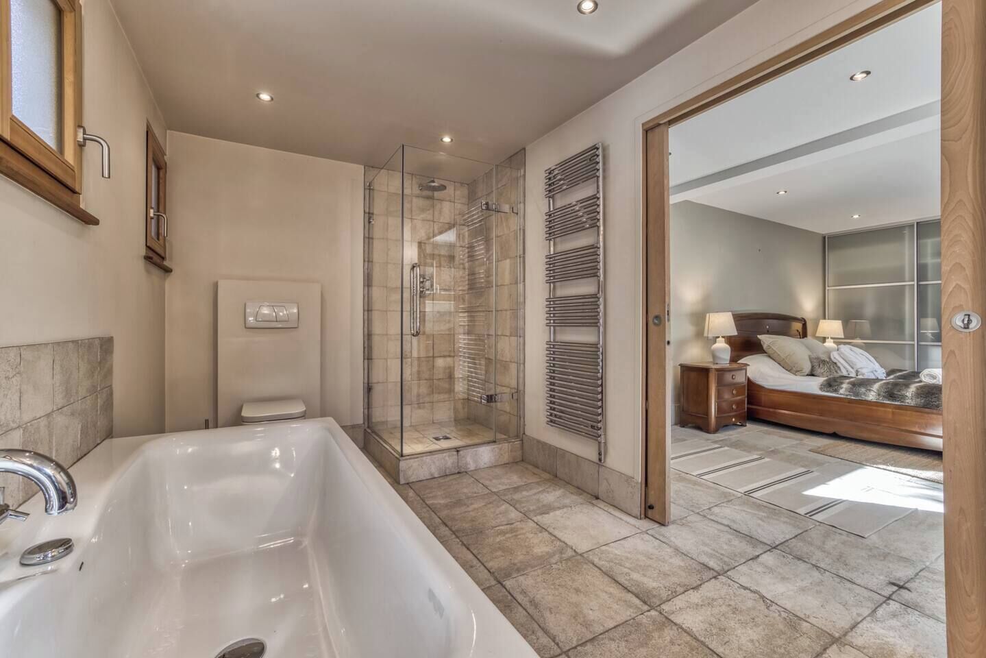A modern bathroom with a large bathtub, a glass-enclosed shower, and a built-in towel rack.