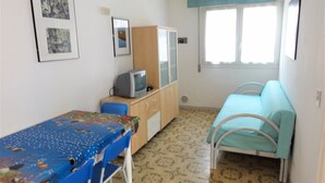A small room with a bed, a desk, a chair, and a television. - Bibione Apartment Near the Beach (San Michele al Tagliamento)