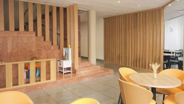 A modern interior with a staircase, wooden panel wall, and yellow chairs around a round table. - Hotel Laitau (Nossa Senhora da Anunciada)