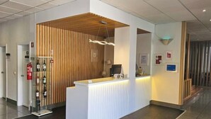 A reception area with a wooden partition, a reception desk, a fire extinguisher, and a wine display. - Hotel Laitau (Nossa Senhora da Anunciada)
